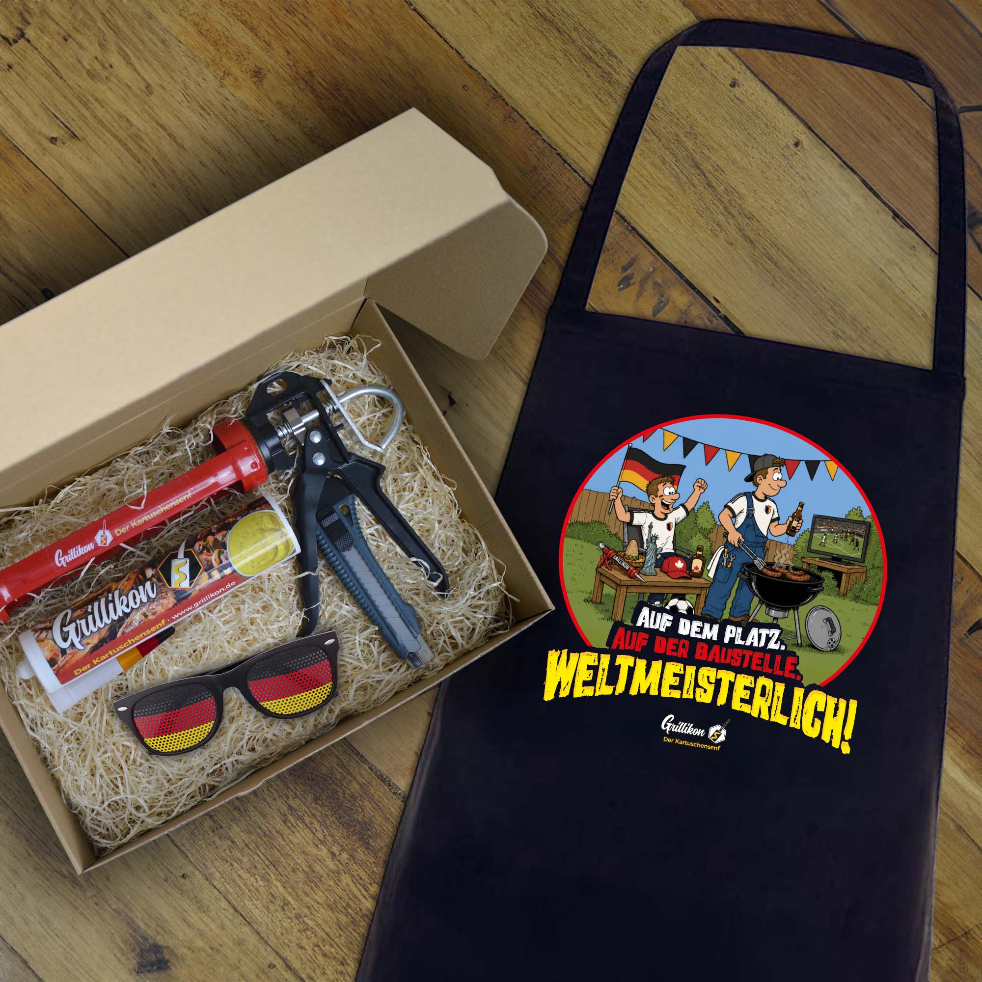 Grillikon Geschenkset „WM-Edition“ mit mittelscharfem Senf in 300 ml Kartusche, Kartuschenpistole, Cuttermesser, Deutschland-Fanbrille und Grillschürze im Geschenkkarton mit Holzwolle