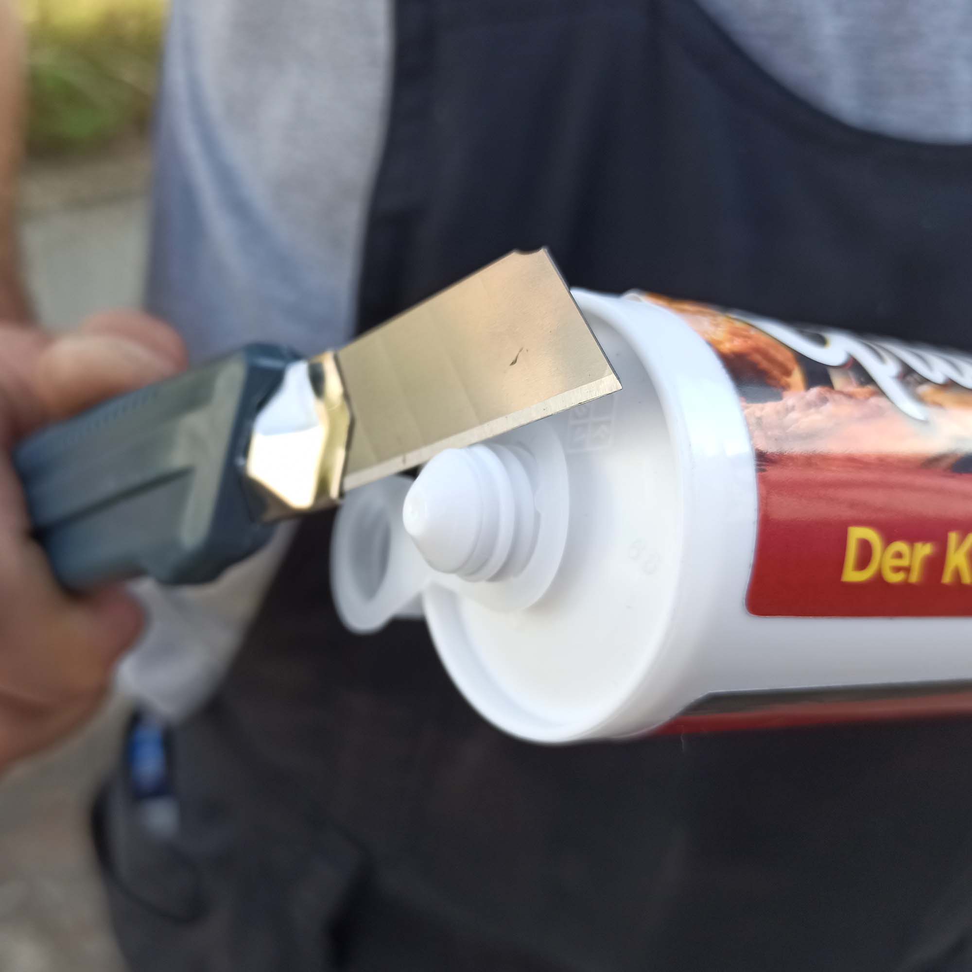 Nahaufnahme: Cuttermesser öffnet die 300 ml Senfkartusche aus dem Grillikon Geschenkset „WM-Edition“ mit mittelscharfem Manufaktursenf, Kartuschenpistole und Zubehör.