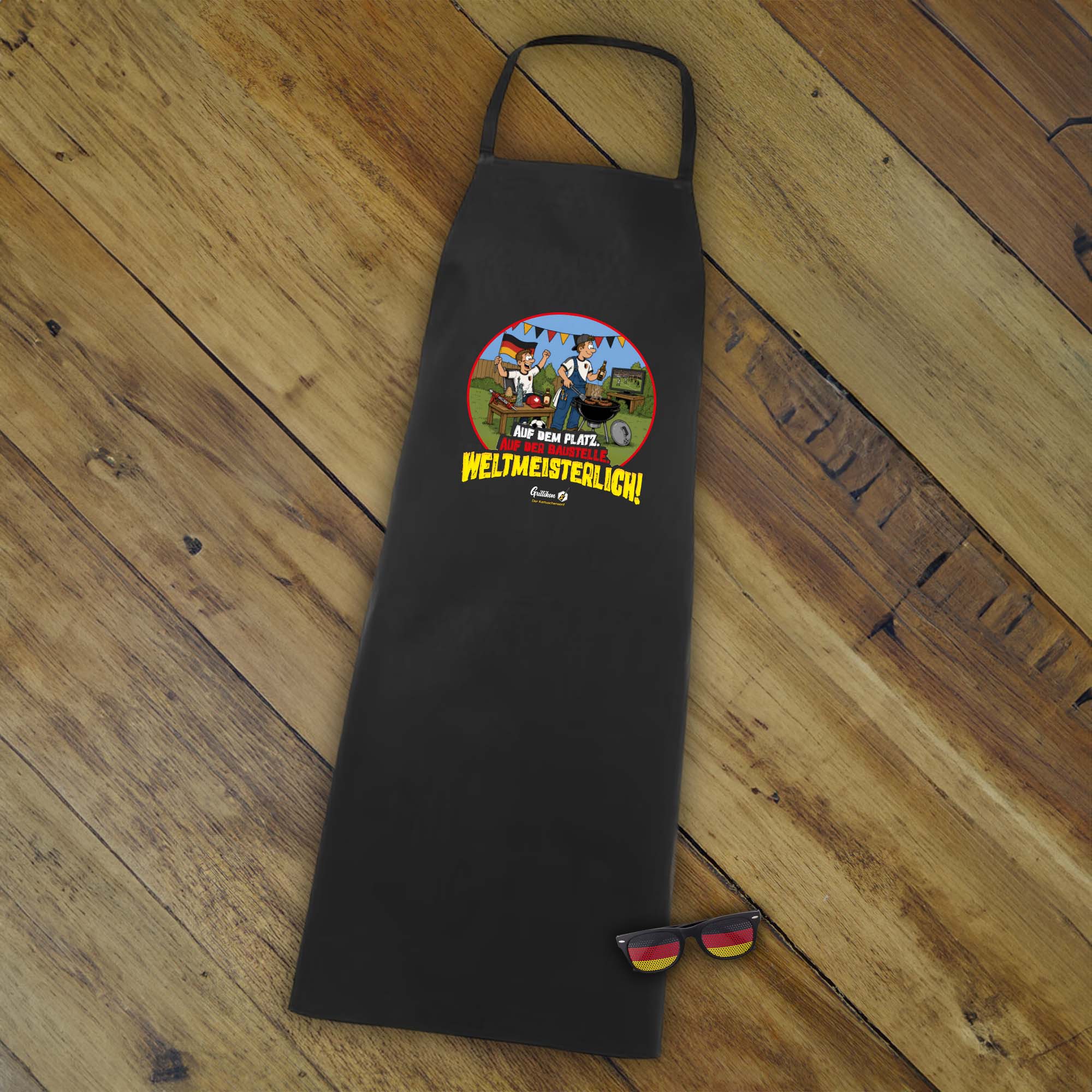 Schwarze Grillschürze mit WM-Motiv „Weltmeisterlich!“ und Deutschland-Fanbrille als Zubehör aus dem Grillikon Geschenkset „WM-Edition“ Senf in 300 ml Kartusche